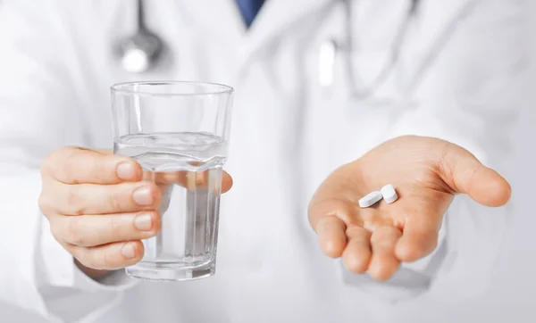 医生给的白色药片和水的玻璃的手 — 图库照片