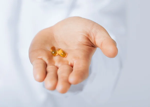 Doctor hands giving capsule and glass of water — Stock Photo, Image