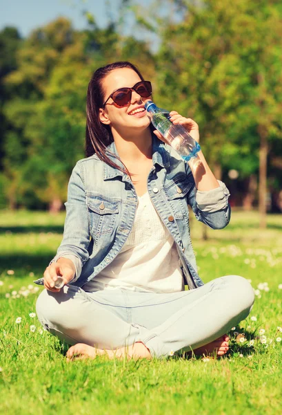 Jeune fille souriante avec bouteille d'eau dans le parc Image En Vente