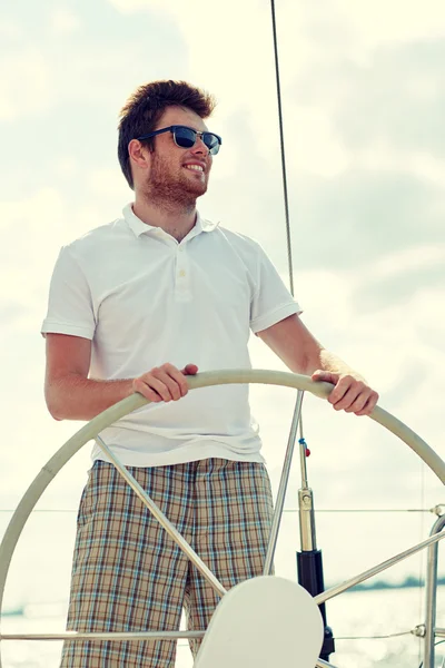 Young man in sunglasses steering wheel on yacht — Stock Photo, Image