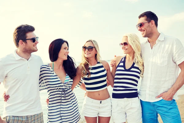 Lachende vrienden in zonnebril praten op strand — Stockfoto