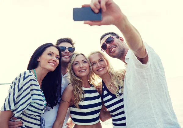 Happy přátelé na pláži a přijetí selfie — Stock fotografie