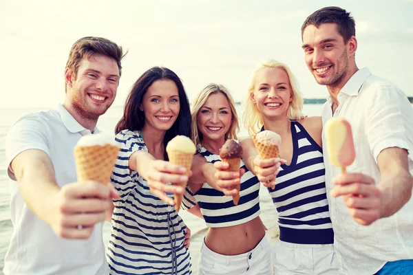 Lachende vrienden eten van ijs op strand — Stockfoto