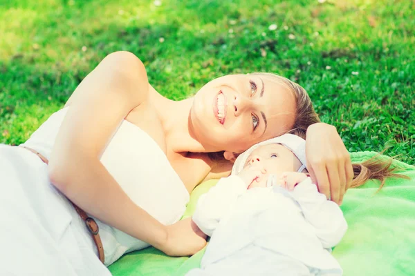 Feliz madre acostada con un pequeño bebé sobre una manta — Foto de Stock