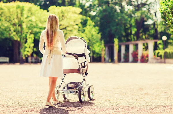 Glad mamma med barnvagn i park — Stockfoto