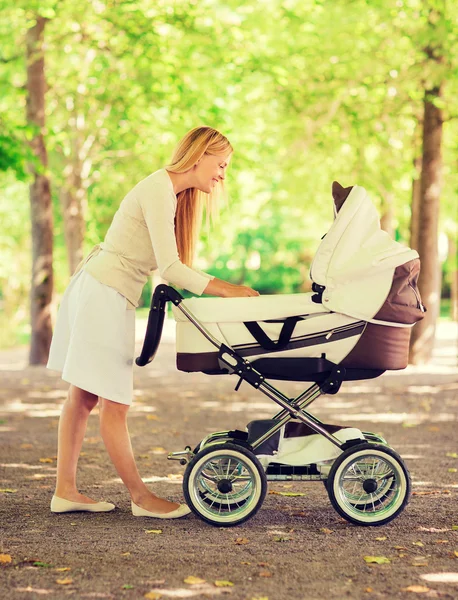 Glad mamma med barnvagn i park — Stockfoto