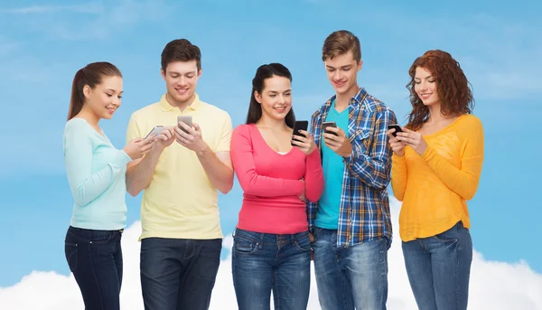 Grupo de adolescentes sonrientes con teléfonos inteligentes — Foto de Stock