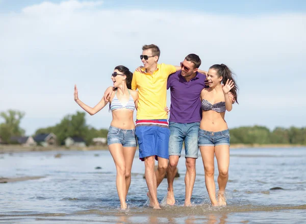Group of happy friends walking along beach — Stock Photo, Image