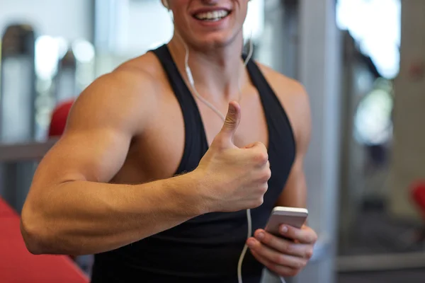 Homem feliz com smartphone e fones de ouvido no ginásio — Fotografia de Stock