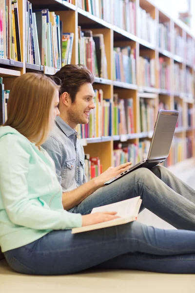 Glada studenter med laptop i biblioteket — Stockfoto