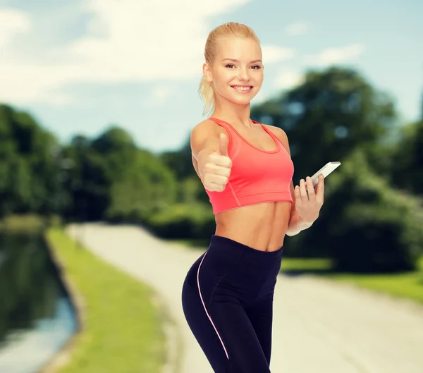 Lachende sportieve vrouw met smartphone — Stockfoto