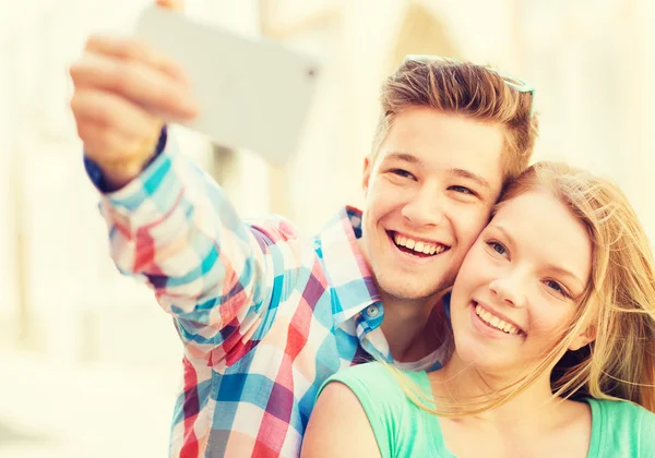 Casal sorridente com smartphone na cidade — Fotografia de Stock