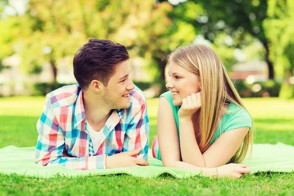 Coppia sorridente sdraiata su una coperta nel parco — Foto Stock