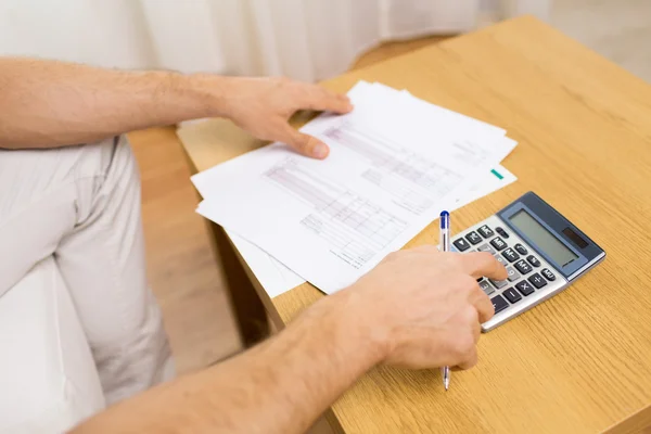 Close up de homem com papéis e calculadora em casa — Fotografia de Stock