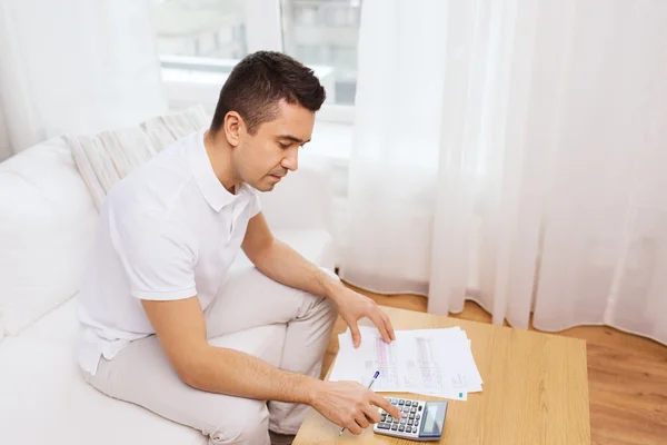 Homme avec des papiers et calculatrice à la maison — Photo