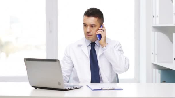 Doctor with laptop calling on smartphone — Stock Video