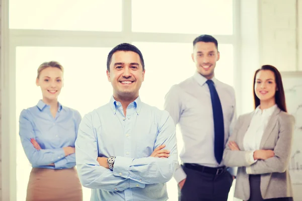 Hombre de negocios sonriente en la oficina con el equipo en la espalda —  Fotos de Stock