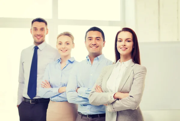 Empresária sorridente no cargo com equipe nas costas — Fotografia de Stock