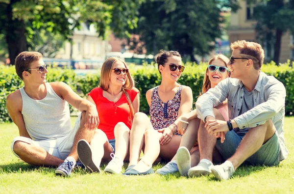 Groep lachende vrienden buiten zitten op gras — Stockfoto