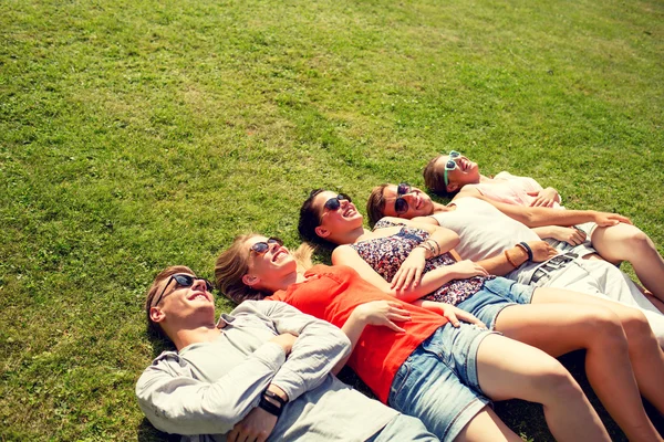 Groupe d'amis souriants couchés sur l'herbe à l'extérieur — Photo