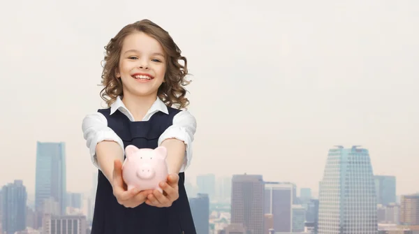 Menina feliz segurando porquinho banco em palmas — Fotografia de Stock