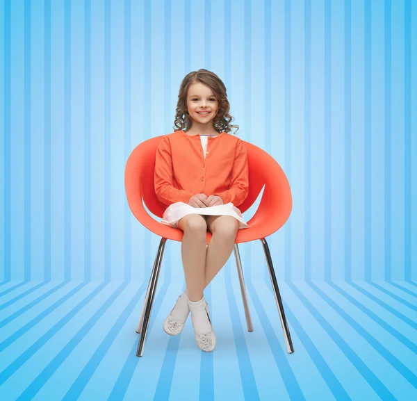 Lycklig liten flicka sitter på designer stol — Stockfoto