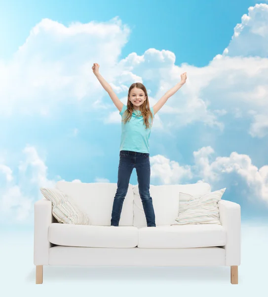 Smiling little girl jumping on sofa — Stock Photo, Image