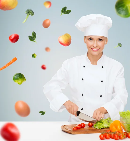 Sorridente chef feminino cortar legumes — Fotografia de Stock