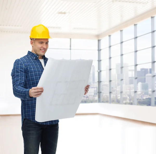 Glimlachend mannelijke bouwer in helm met blauwdruk — Stockfoto