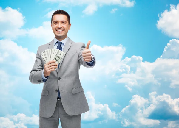 Sonriente hombre de negocios con dinero mostrando pulgares hacia arriba — Foto de Stock