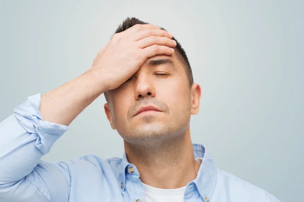 Hombre infeliz con los ojos cerrados tocando su frente — Foto de Stock