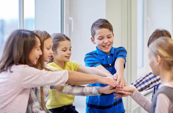 Grupp av leende skola barn att sätta händerna på toppen — Stockfoto