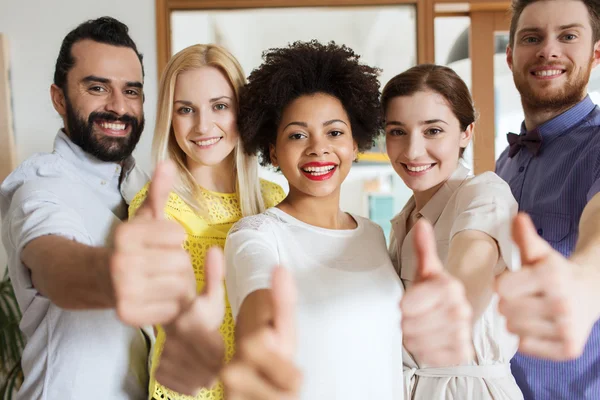 Happy creative team showing thumbs up in office — Stock Photo, Image