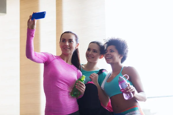 happy women with smartphone taking selfie in gym