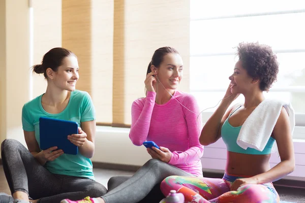 Gelukkig vrouwen luisteren naar muziek in de sportschool — Stockfoto