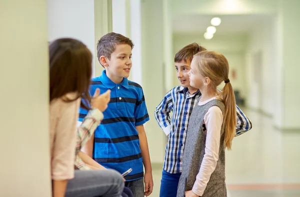 Gruppe lächelnder Schulkinder unterhält sich auf dem Flur Stockfoto