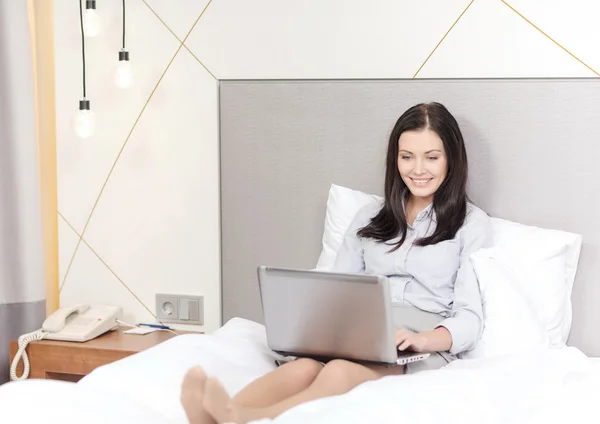 Feliz mujer de negocios con portátil en la habitación de hotel —  Fotos de Stock