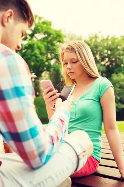 Casal com smartphones no parque — Fotografia de Stock