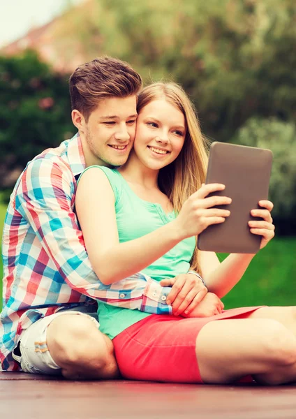 Sonriente pareja con tableta pc haciendo selfie — Foto de Stock