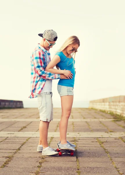 Sonriente pareja con monopatín al aire libre — Foto de Stock