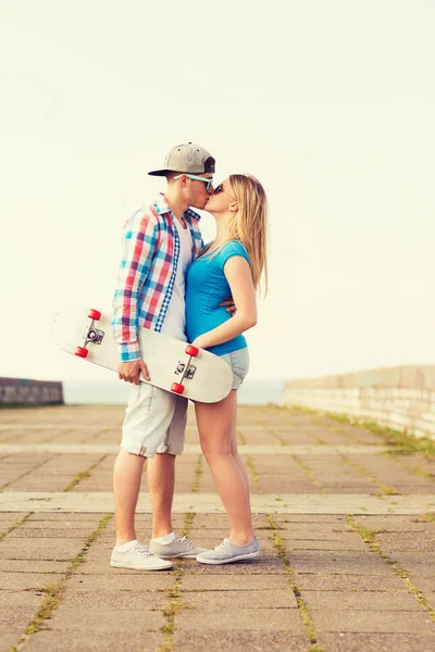 Mosolyogva pár gördeszka csók szabadban — Stock Fotó