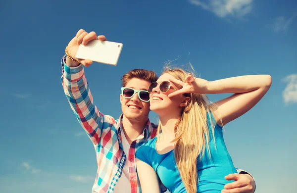 Sorrindo casal com smartphone fazendo selfie — Fotografia de Stock