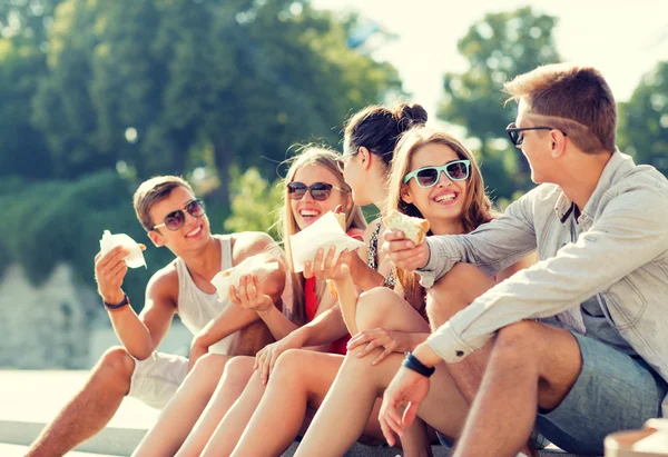 Groep lachende vrienden zitten op het stadsplein — Stockfoto