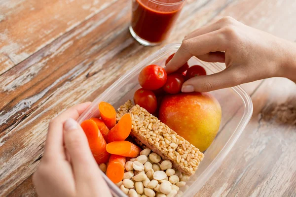 close up of hands with vegetarian food in box