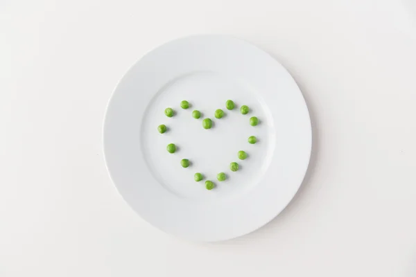 Close up of plate with peas  in heart shape — Stock Photo, Image