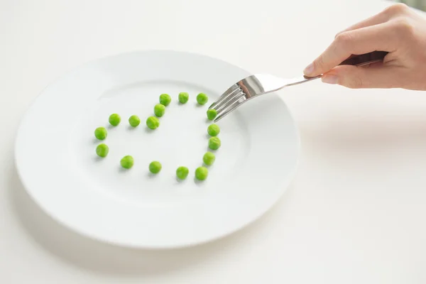 close up of woman with fork eating peas