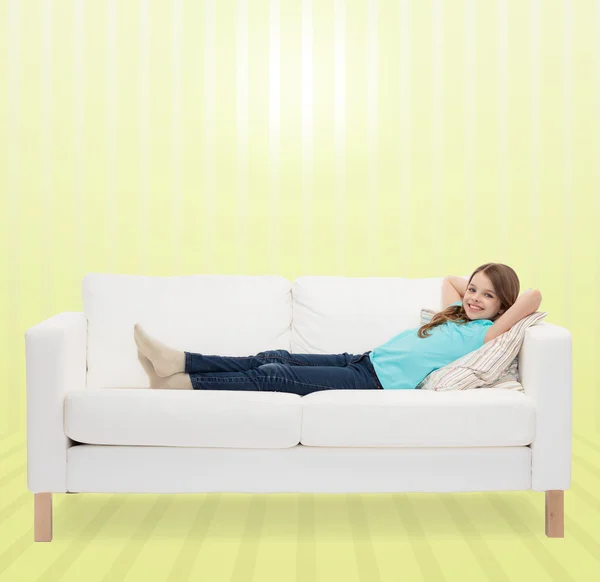 Lächelndes kleines Mädchen auf Sofa liegend — Stockfoto