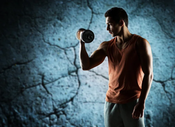 Young man with dumbbell flexing biceps — Stock Photo, Image