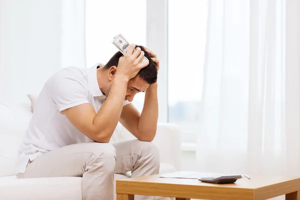 Man with money and calculator at home — Stock Photo, Image