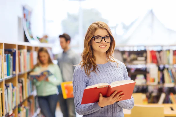 Happy student girl or woman with book in library — Stock Photo, Image